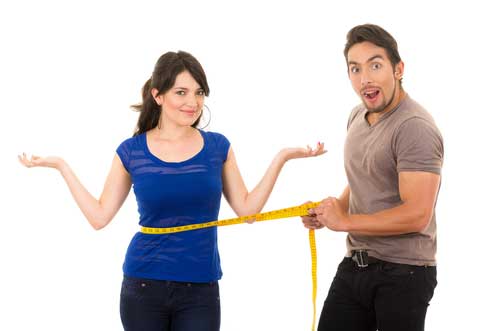 A couple measuring waist progress with a tape as part of tracking healthy habits